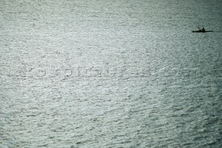 A lone sea kayaker paddles across the shimmering surface of Lake Pend Oreille in Sandpoint, Idaho