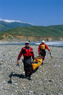 Writer Peter Heller and friend Landis Arnold portage their sea kayak along the beach at Andrew Molera State Park toward the mouth of the Big Sur River along the central coast of California.