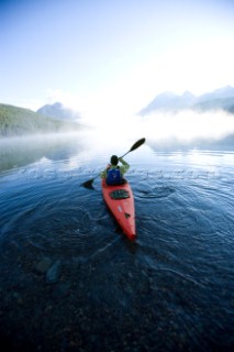 Andy Fueling paddles his kayak alone at dawn on Bowman Lake in Glacier National Park, Montana