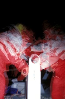 Slow shutter speed image of crew grinding winches on ocean racing yacht
