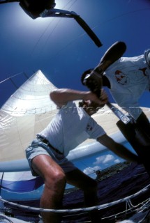 Two crew members work a coffee grinder winch onbaord a racing yacht