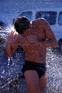 A man is soaked by water from a hose pipe