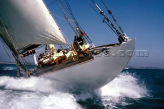 Close up of bow of classic yacht crashing through a wave