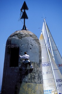 A man in a harness repairs the pillar of a cardinal marker buoy near Saint-Tropez, France