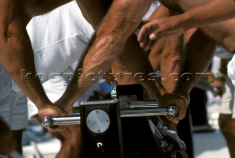 Close up of hands on the coffee grinder winches of a racing yacht