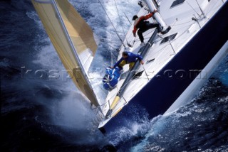 Two crew members of the foredeck of a maxi yacht in rough seas