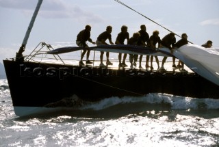 Crew on a racing yacht struggle to pull the spinnaker on board as it drags in the water