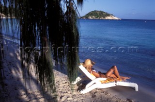 Woman in straw hat lying on sun lounger looking out to sea