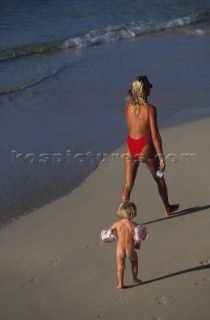 Woman and young child walking along sandy beach