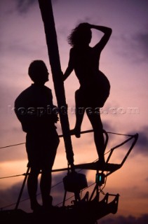 Couple standing on bow of cruising yacht.