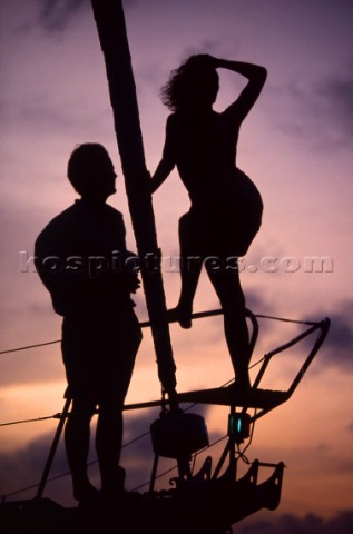 Couple standing on bow of cruising yacht