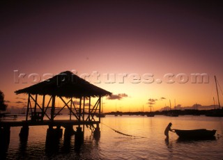Fisherman with boat by hut on wooden dock at sunset, Greneda