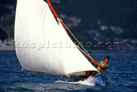 Two fishermen racing local wooden fishing boat Grenada Caribbean