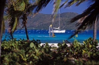 Windsurfer sails passed anchored yacht off the island of Eustatia, Caribbean