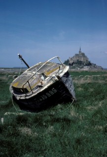 Old fishing boat stranded at low tide between the Brittany coast and the rock of Mont St Michel