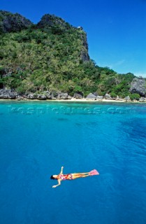 Woman floating on her back in clear blue water, Fiji