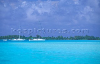 Two sailing yachts at anchor in shallow water