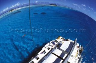 View from masthead of cruising catamaran anchored in clear blue water