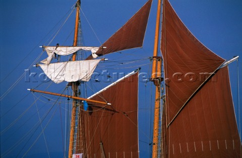 Sailor furling a square sail onboard a classic schooner