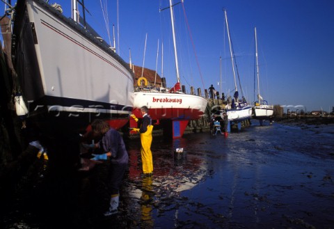 People painting the bottom of a yacht  Bosham harbour UK 