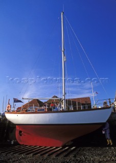 Maintenance on a classic sloop at low tide - Bosham harbour, UK