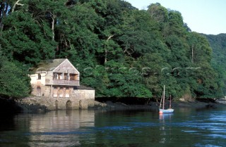 Dinghy moored to buoy by house on the river Fal, Falmouth, Cornwall, UK