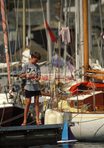 Boy with model yacht in Falmouth harbour Devon UK