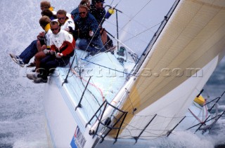 Crew on rail of racing yacht in rough seas