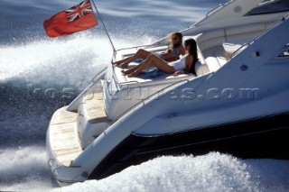 Two women lying on sun platform at the aft of a Sunseeker power boat