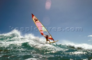 Windsurfer speeds over a wave in windy conditions