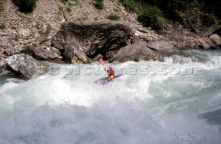 A conoeist paddles into fierce rapids.