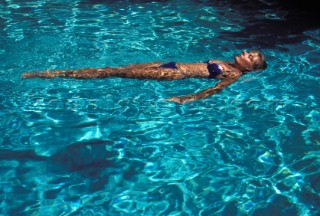 Woman floating on her back in clear shallow water