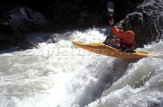 Canoeist paddles down fast flowing rapids