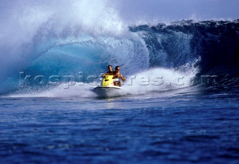Holiday couple on a yellow waverider having an exciting time surfing huge waves