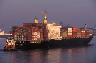 Loaded container ship and tug boat in shipping channel, Solent, UK