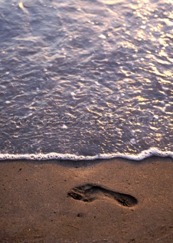 Footprint in wet sand at waters edge