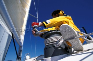 Crew member grinding winch with foot on line