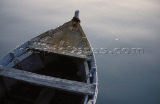 Detail of old wooden dinghy on calm water