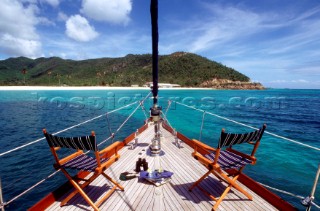 Two empty chairs on the deck of a luxury yacht moored in a bay