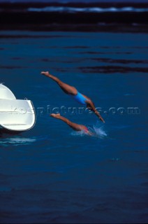 Two girls diving off a catamaran