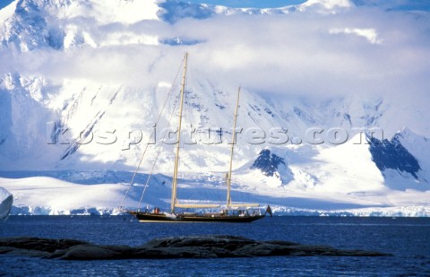 Maxi cruising yacht anchored in a bay beneath snow covered mountains