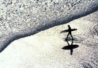 Silhouette of surfer with board on beach