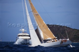 Maxi racing yacht passing the bow of a large motor yacht under way