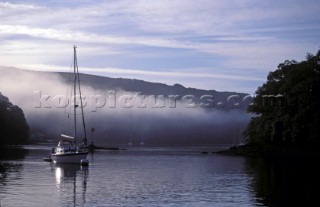 Yacht moored on the River Dart at Dittisham in the mist and fog