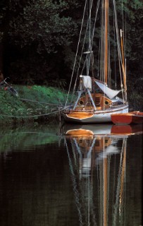 Reflection of moored wooden boat in still surface of river