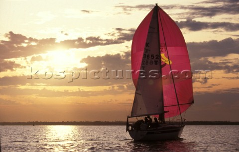 Cruising yacht sailing into sunset UK