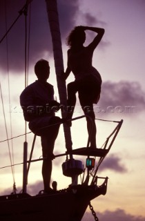 Silhouette of couple on bow of anchored cruising yacht