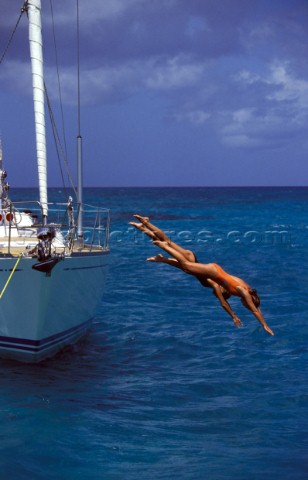 Two girls dive off the side of an anchored Swan yacht