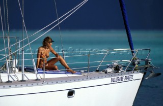Girl resting on the foredeck of a French cruising charter yacht