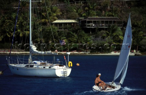 Dinghy sailing past a moored charter yacht by Saba Rock